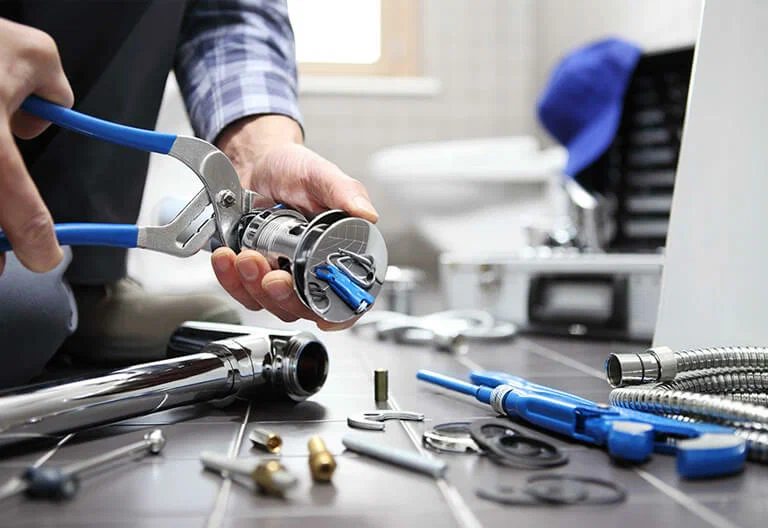 Technician repairing a plumbing fixture with professional tools in Chambersburg