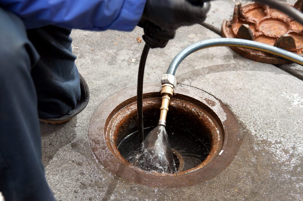 Plumber hydro jetting a sewer line through a manhole in Chambersburg