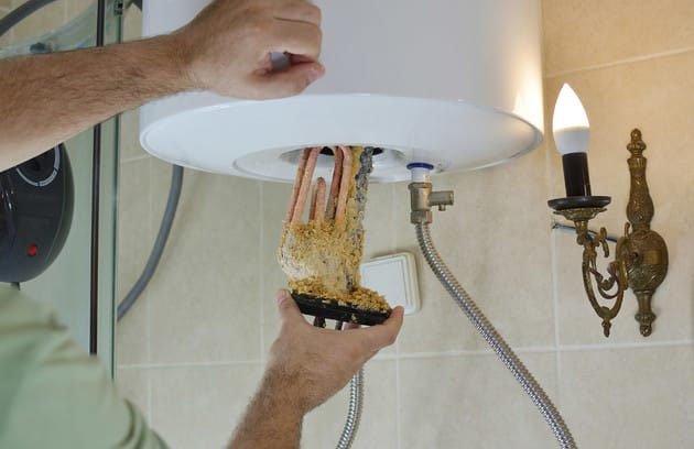 Technician removing mineral buildup from a water heater in Chambersburg